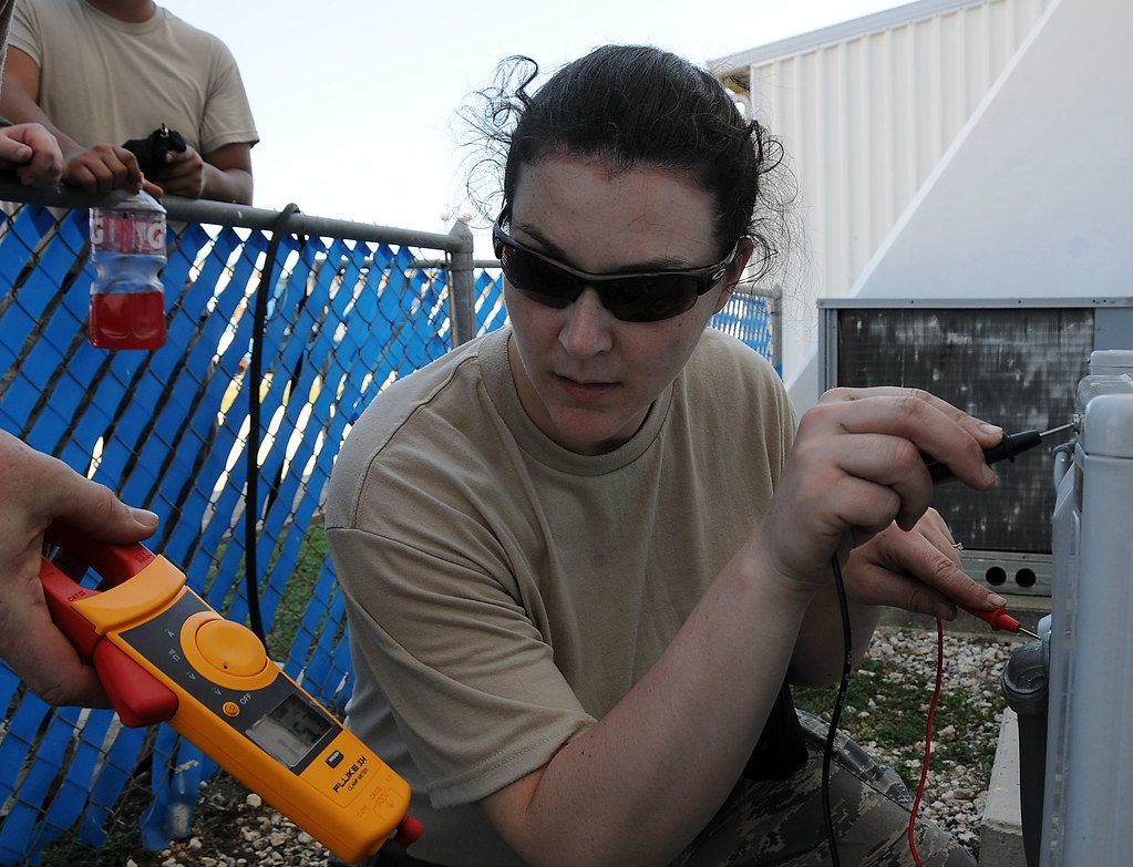 Technician using test equipment near an air conditioning unit