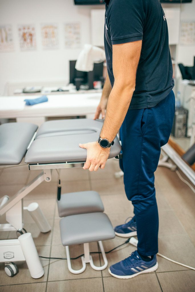Physiotherapist adjusting clinical equipment