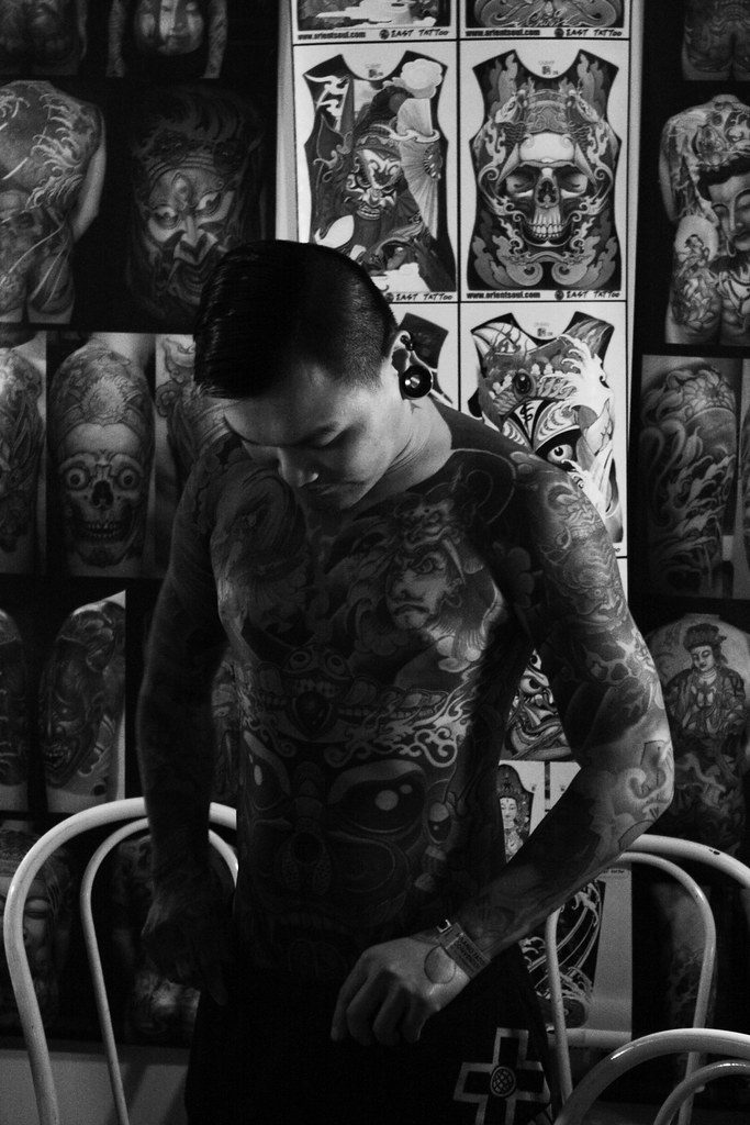 Tattoo artist in a studio with flash on the wall