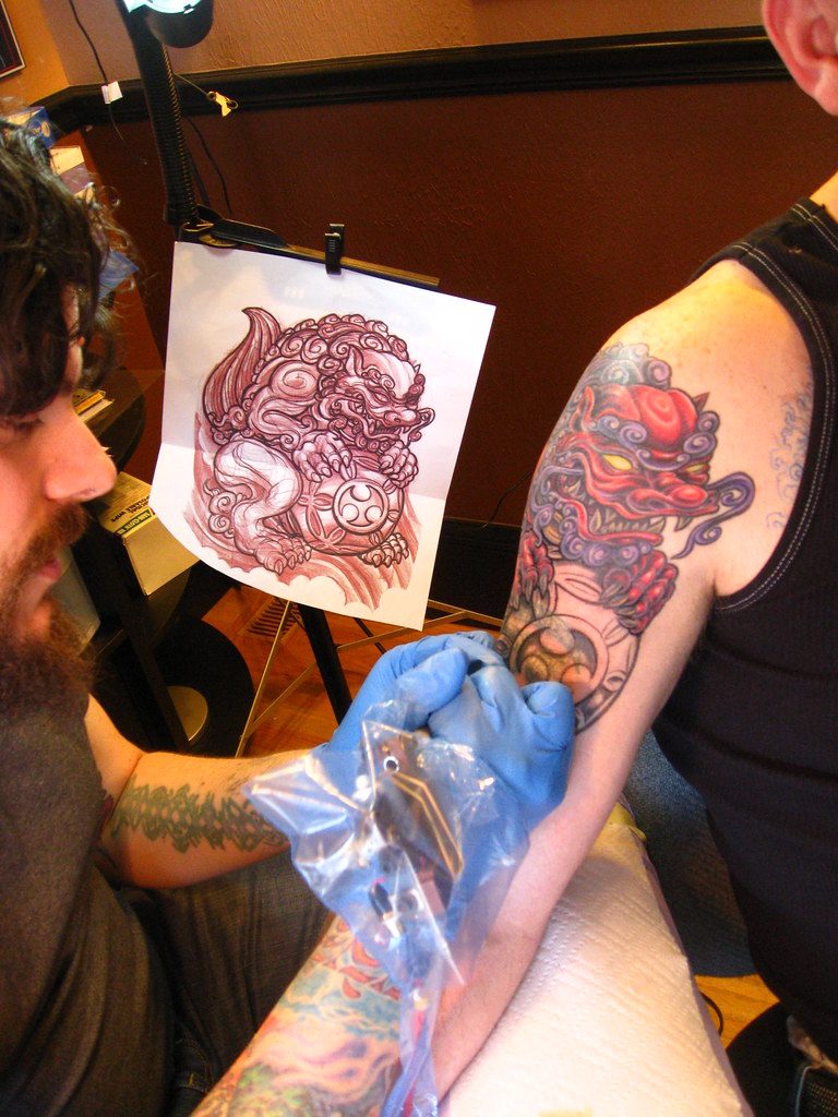 Tattoo artist working from a stencil reference